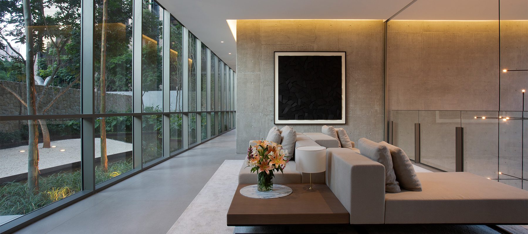 Hall social do Casa Brasileira Itaim, com pé-direito alto, vidro e vista para o jardim