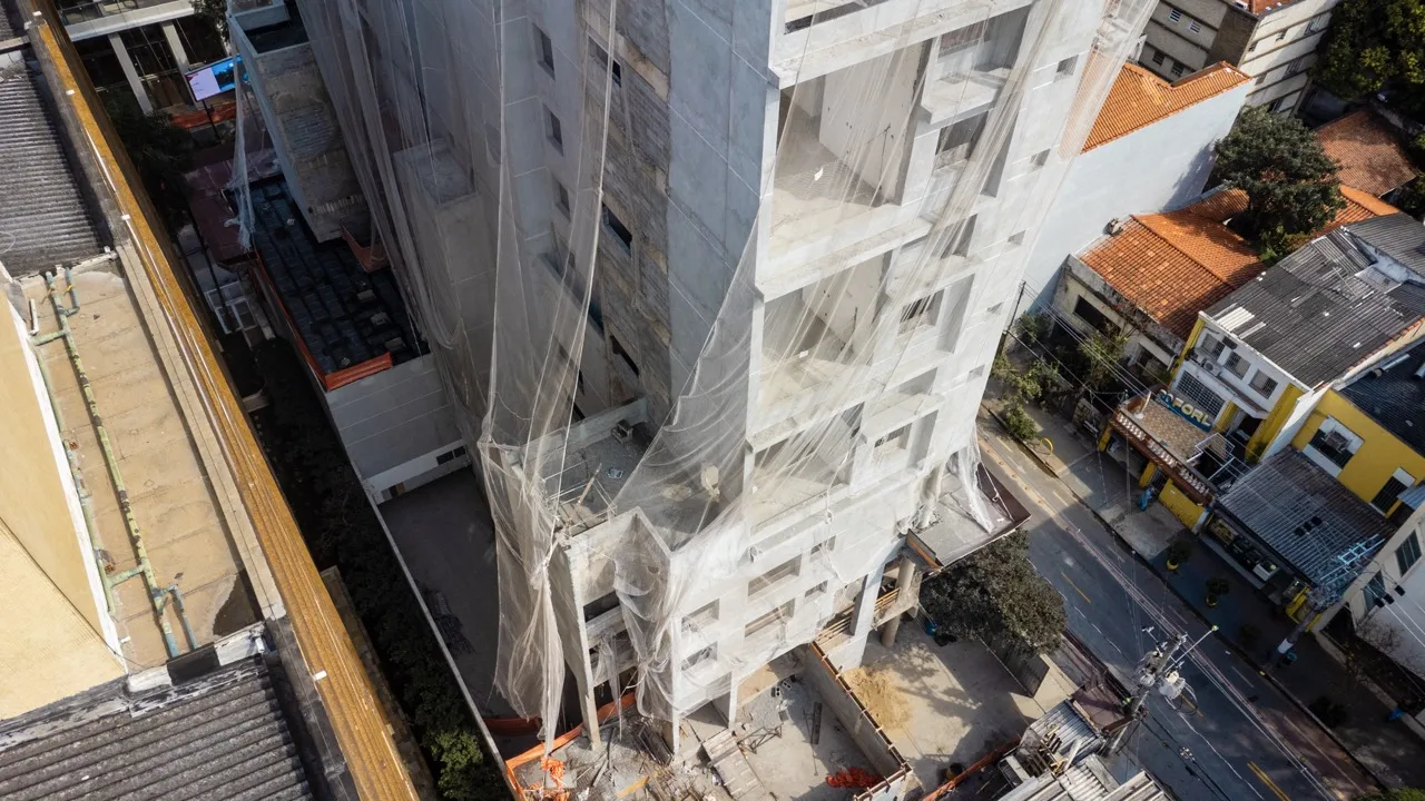 Foto real da obra do Artur 73: fachada do edifício já executada, com esquadrias instaladas e revestimento aparente, registro do andamento da construção em Pinheiros