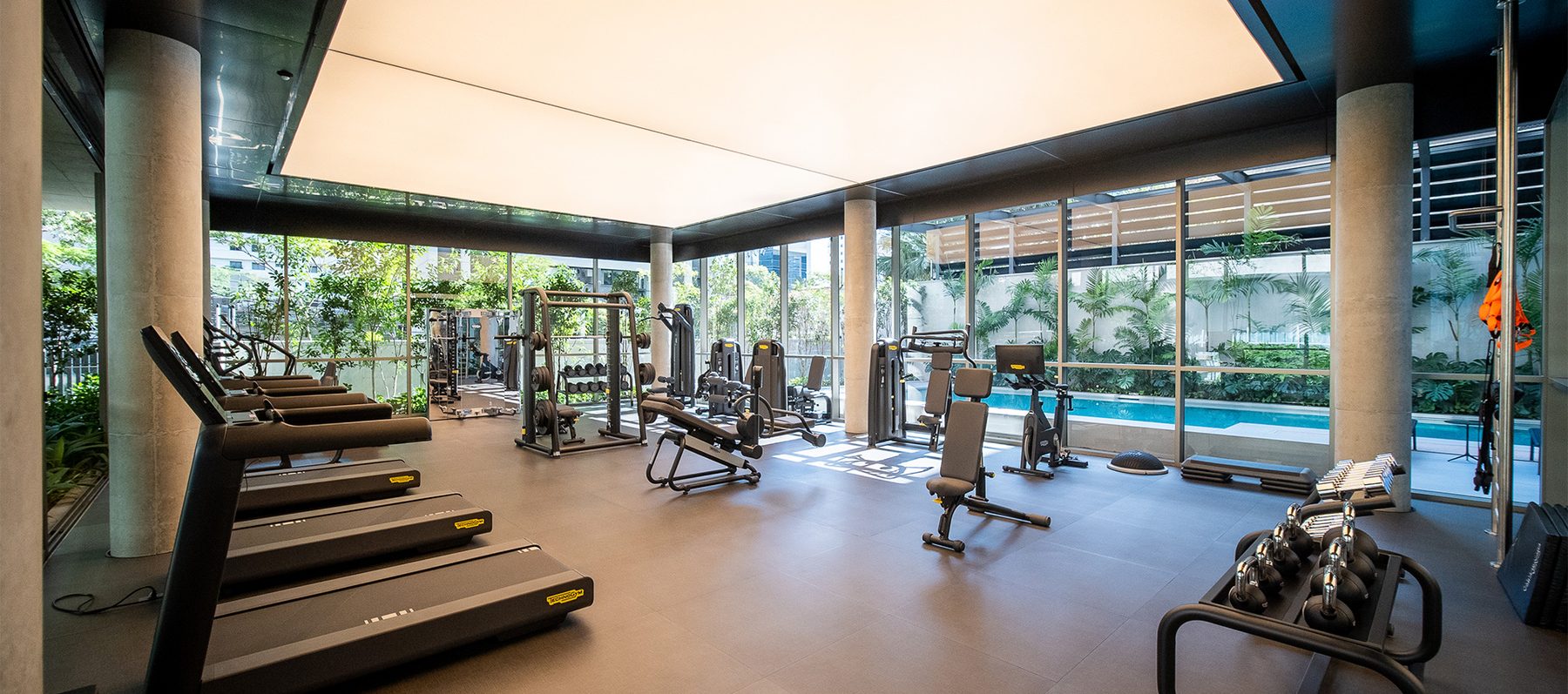 Academia equipada Technogym do Casa Brasileira Itaim, com esquadrias de vidro voltadas para a piscina