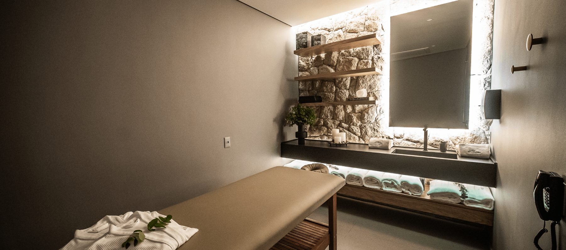 Sala de massagem do spa do Casa Brasileira Itaim, com bancada em pedra e revestimento natural