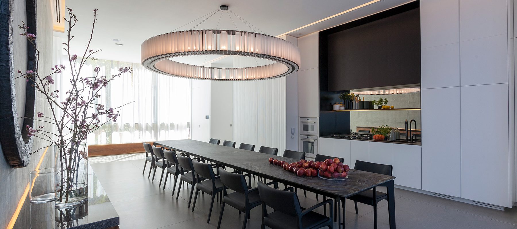 Espaço gourmet do Casa Brasileira Itaim, com mesa longa e luminária circular autoral