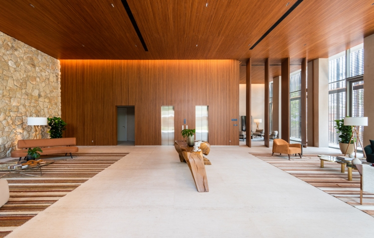 Lobby do Casa Leopoldo com pé-direito duplo, forro de madeira e parede de pedra natural, em São Paulo